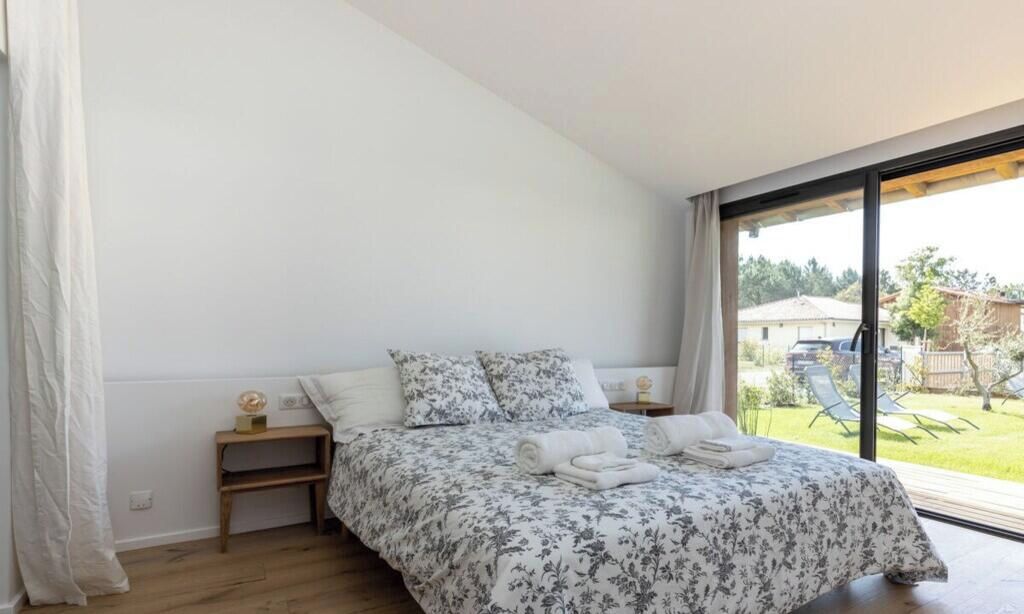Un dormitorio con una cama grande, una mesita de noche y vistas al exterior.