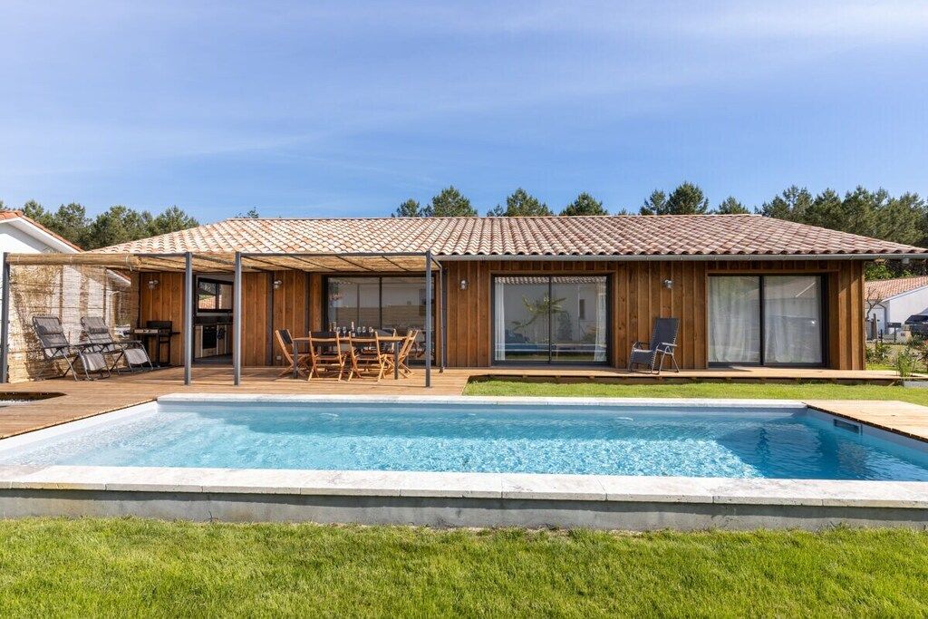 A modern house with a swimming pool, wooden deck, and outdoor furniture.