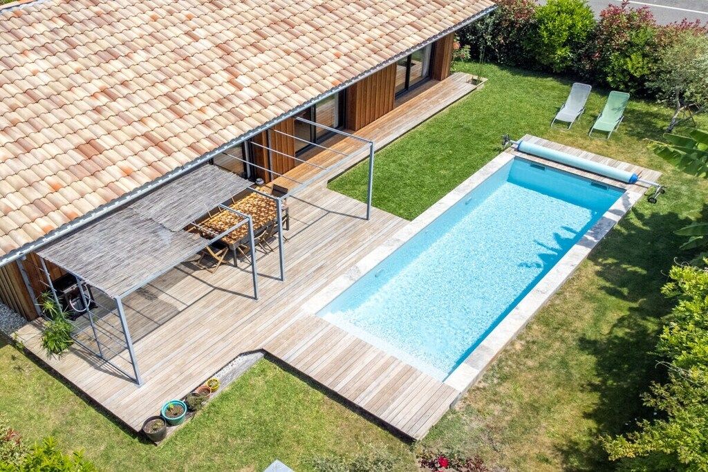 A modern house with a swimming pool, a deck, and a covered outdoor seating area.