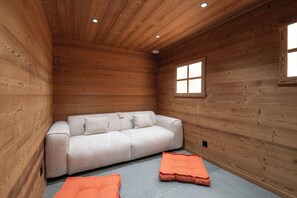 Ein Holzblockbau-Innenraum mit einer Couch und zwei Kissen auf dem Boden.