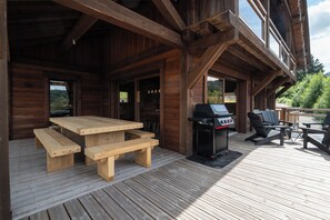 Eine Holzterrasse mit Picknicktisch und Grillplatz.