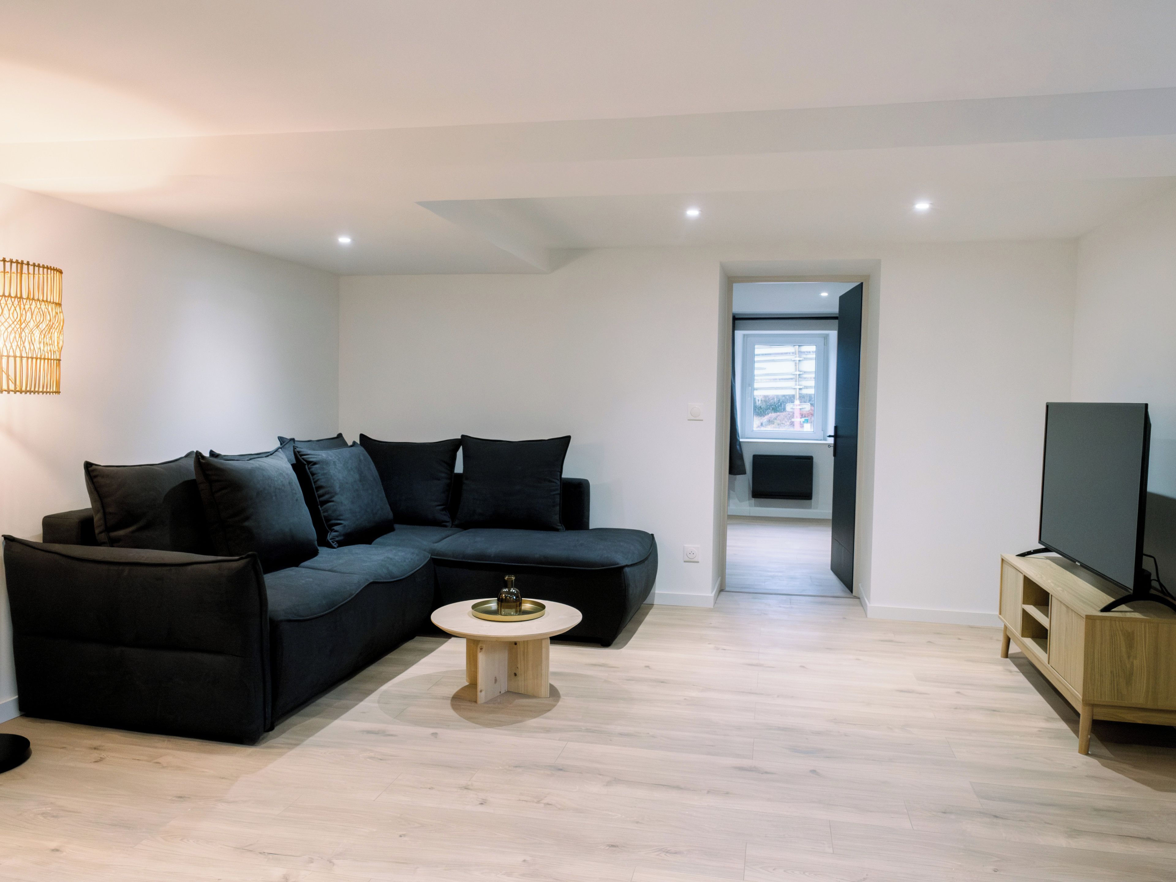 A modern living room with a dark-colored sofa, a small round coffee table, and a television on a wooden stand.