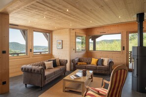 A cozy living room with two sofas, a coffee table, and a fireplace. - ✨ Chalet Farnes 800 – Brand new Luxury Chalet with Panoramic Lake Views (Gérardmer)