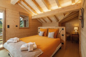 Ein Schlafzimmer aus Holz mit einem Bett, Kissen, einem Nachttisch und einem Fenster.