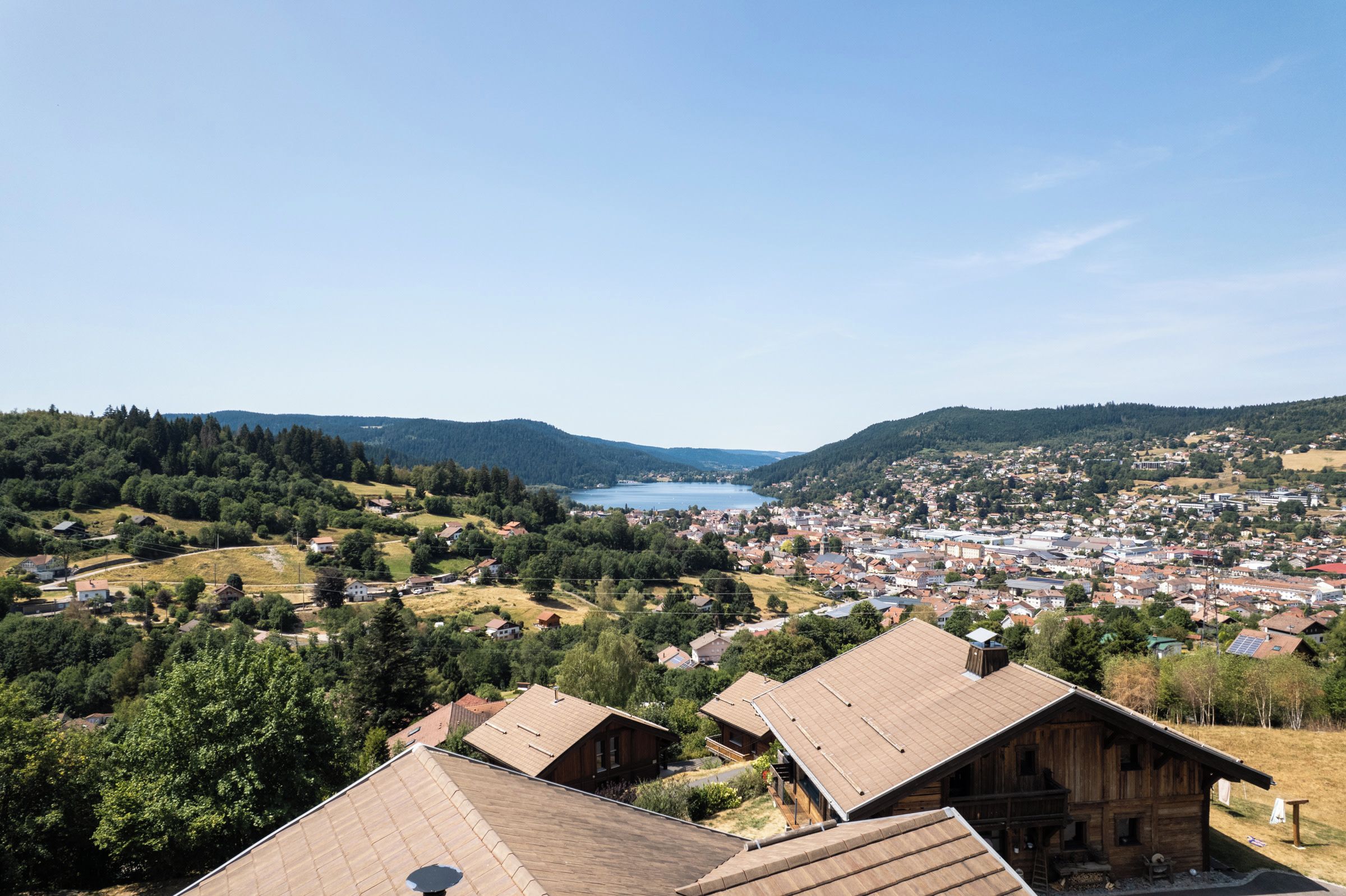 Un pueblo con un lago al fondo, rodeado de colinas y vegetación.