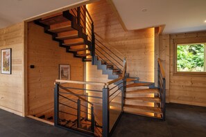 Eine moderne Holztreppe mit Glasgeländer, die zu einer oberen Etage führt.
