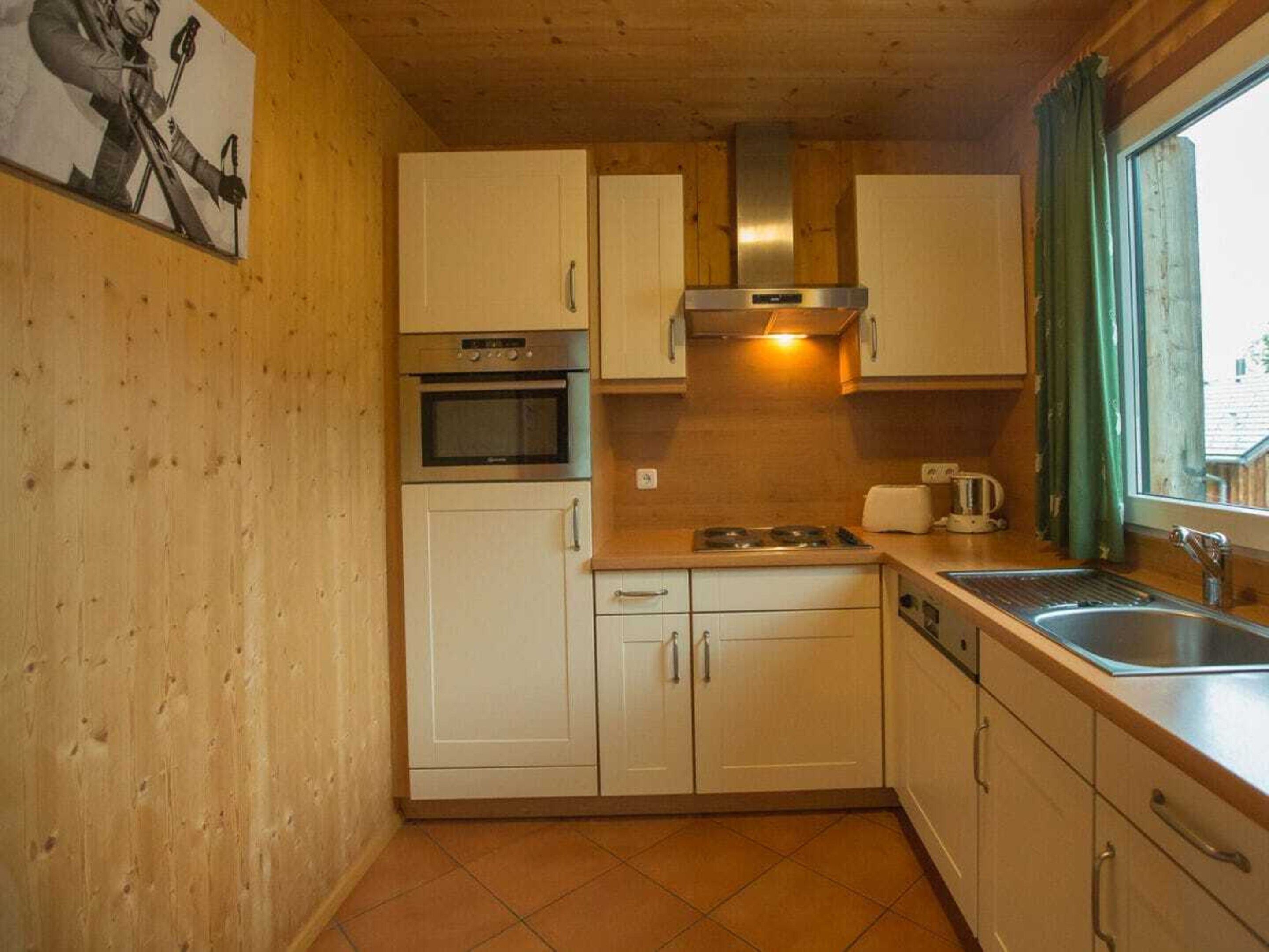 A compact kitchen with white cabinets, a stove, oven, and a sink.
