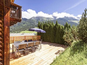 A wooden deck with a table and chairs, overlooking a mountainous landscape. - Cabin in Annaberg With Swimming Pool (Annaberg-Lungoetz)