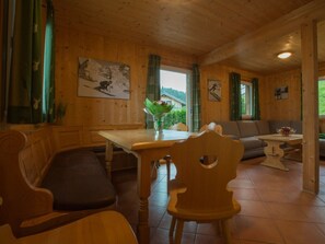 Interior de madeira com uma mesa de jantar, cadeiras, um sofá e obras de arte nas paredes.