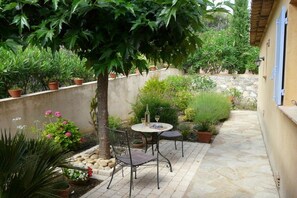 An outdoor patio with a table and chairs, surrounded by potted plants and a stone wall. - Holiday home in Cogolin with swimming pool (Cogolin)
