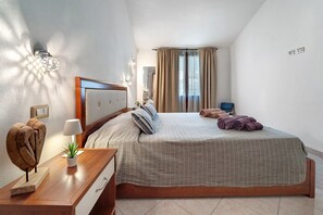 A bedroom with a bed, bedside table, lamp, and a wall-mounted light fixture. - Angela House Teulada – Comfort and Relaxation in the Heart of Southern Sardinia (Teulada)