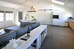 A modern living area with a sofa, a dining table, and a kitchen with a refrigerator. - Holiday home with 1 bedroom (Cadzand-Bad)