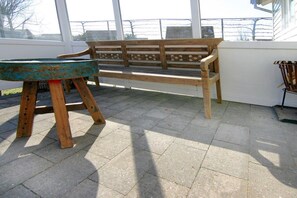 A wooden bench with a metal table in front of a large window. - Holiday home with 1 bedroom (Cadzand-Bad)