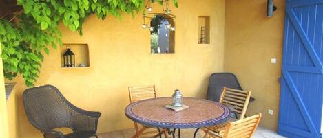An outdoor patio with a round table and four chairs, a lantern, and a blue gate.