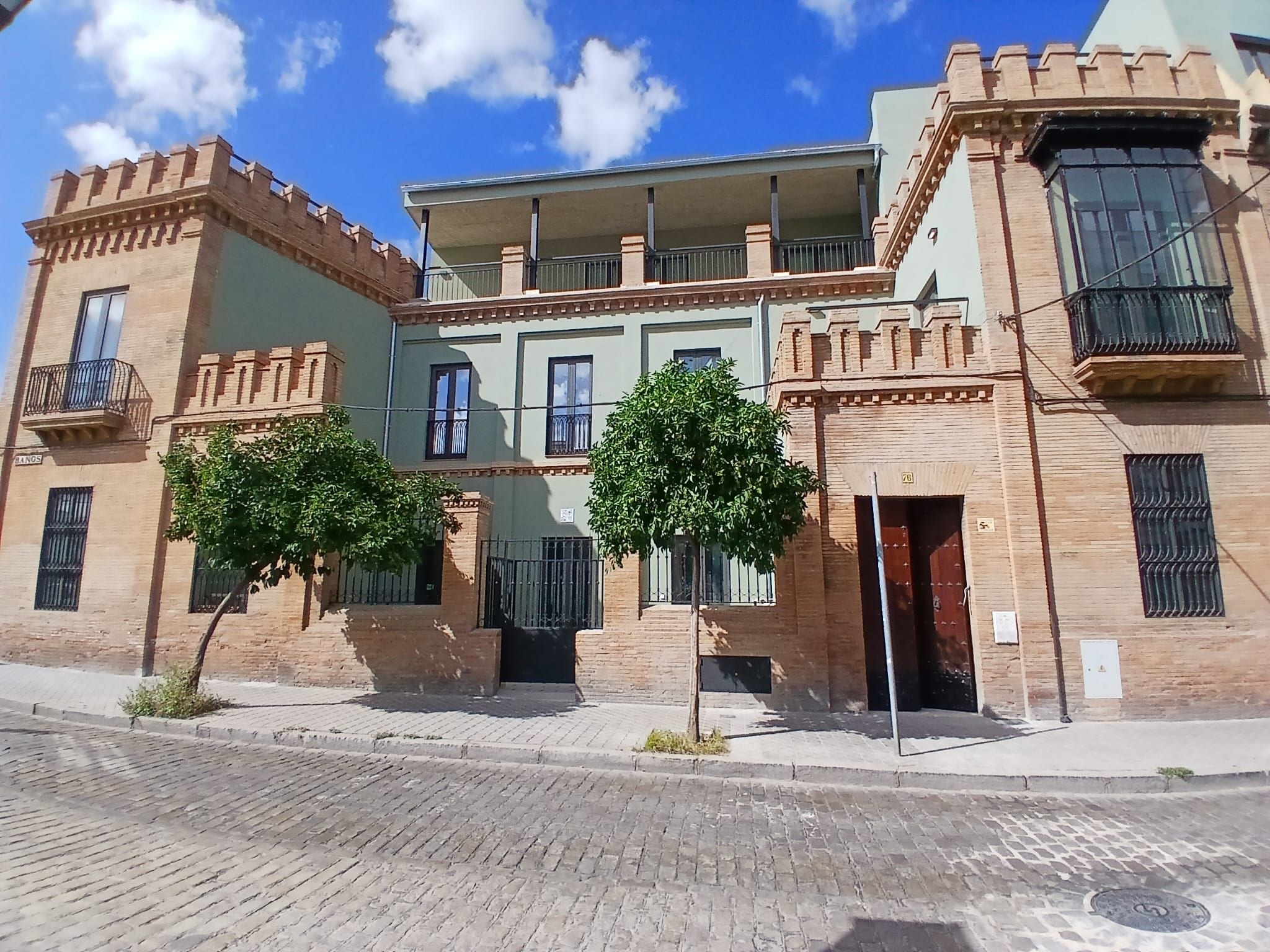 Ein mehrgeschossiges Gebäude mit Ziegel- und Stuckfassade, das Balkone und einen zentralen Innenhof aufweist.