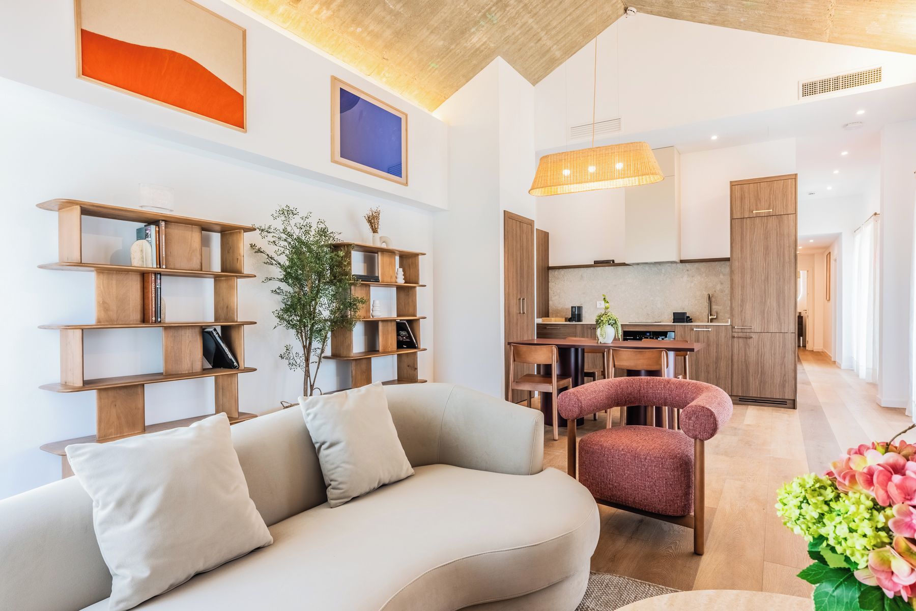 A modern living room with a sofa, a wooden bookshelf, and a dining area with a table and chairs.