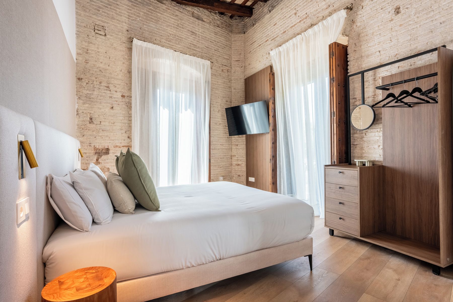 Une chambre à coucher comprenant un lit, un téléviseur fixé au mur, une armoire et un miroir.