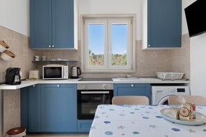A compact kitchen with blue cabinets, a microwave, a coffee maker, and a sink.