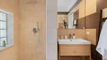 Un baño moderno con ducha, lavamanos y espejo.