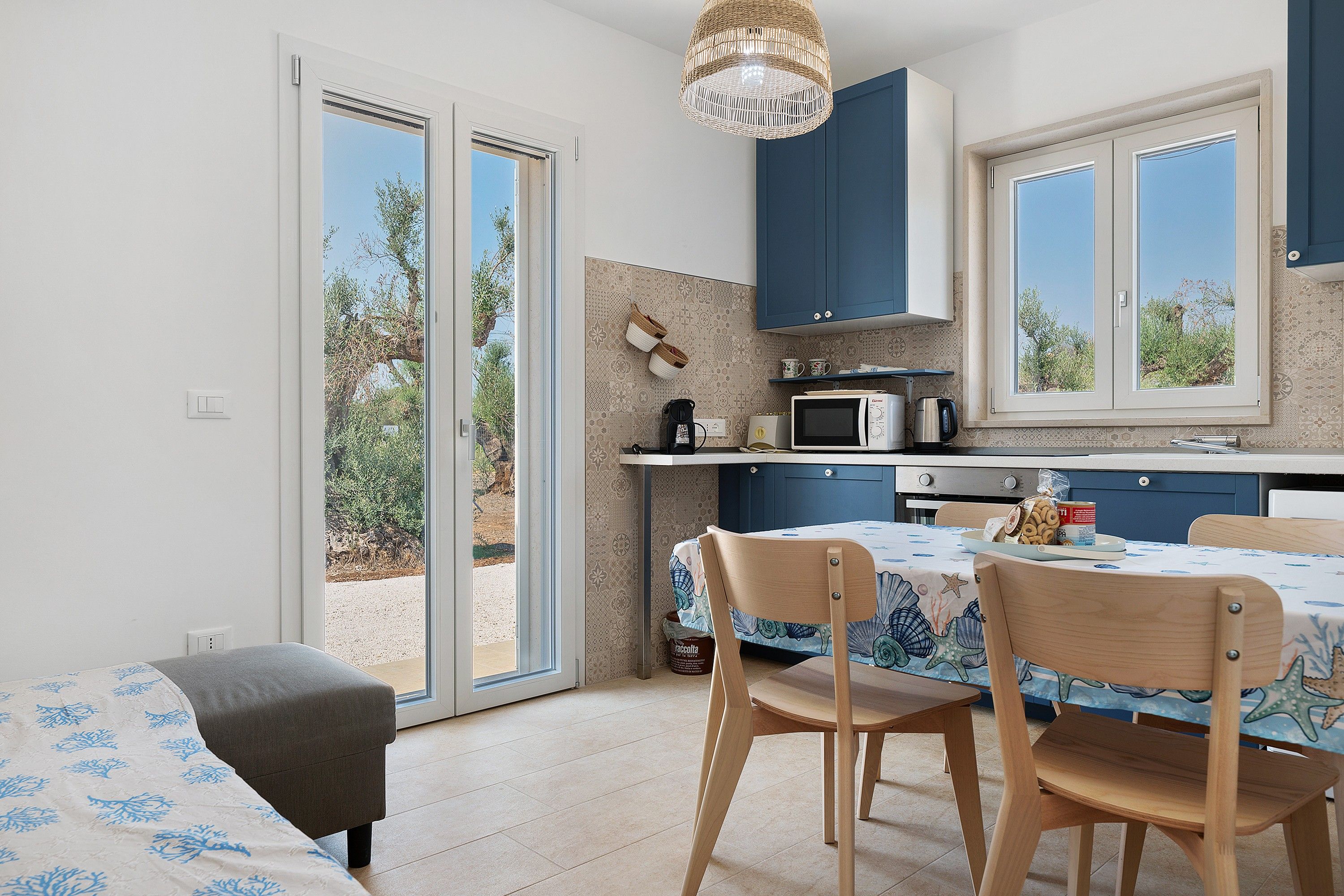 A modern kitchen with a dining area, featuring a sliding glass door, a microwave, and a table set for two.
