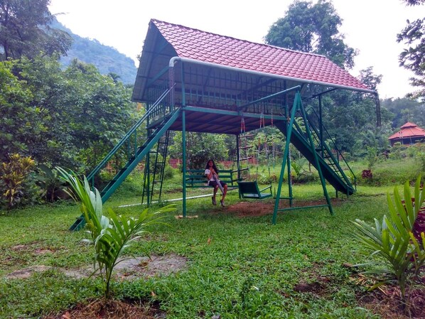 A playground with a swing set and a covered structure.