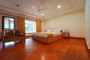Une chambre à coucher avec un lit, un canapé et une fenêtre avec des rideaux.