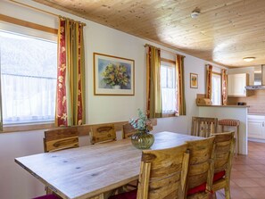 A wooden dining table with chairs, a vase of flowers, and a painting on the wall. - Cabin in Annaberg With Swimming Pool (Annaberg-Lungoetz)