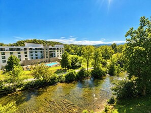 Een hotel met een zwembad, omringd door weelderige begroeiing en een rivier.