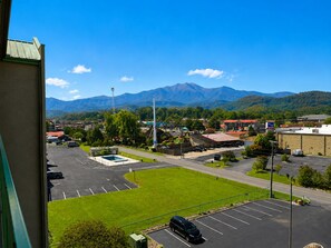 A parking lot with a view of mountains in the distance. - Riverfront Retreat | Balcony + Pool | Heart of Pigeon Forge | FREE Dollywood (Pigeon Forge)