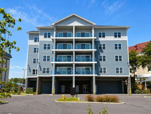 A multi-story building with a central entrance, balconies, and a parking lot. - New Pige Forge Condo | Mtn View - Walk Everywhere (Pigeon Forge)