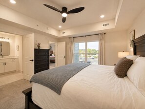 A bedroom with a bed, dresser, ceiling fan, and a view through a window. - New Pige Forge Condo | Walk Everywhere (Pigeon Forge)