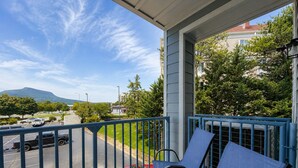 A balcony with a view of a parking lot and a red car, a blue railing, and a clear sky. - New Pige Forge Condo | Mtn View - Walk Everywhere (Pigeon Forge)