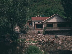 Una casa con un muro de piedra y un estanque al frente.
