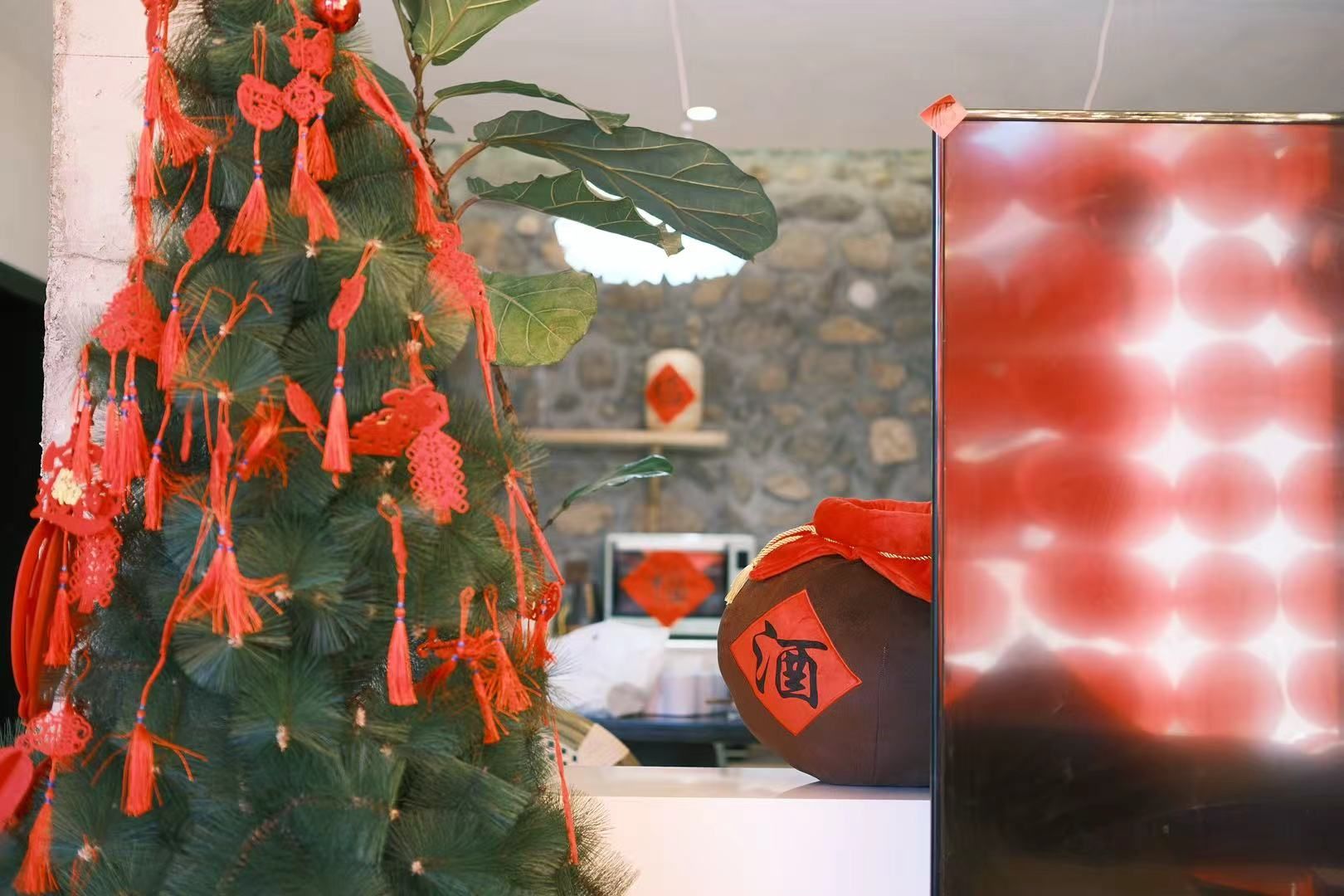 A room with a Christmas tree decorated with red ornaments and a red lantern.