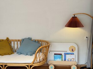 A room with a wicker sofa, a small table with books, and a lamp. - Qiran Rustic Resort Villa (Huairou)