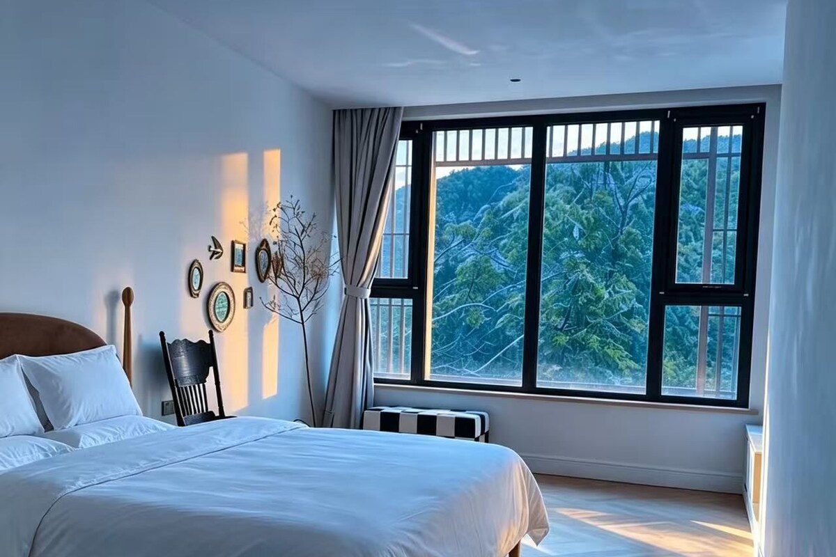 Un dormitorio con un ventanal grande, una cama, una silla y un radiador.
