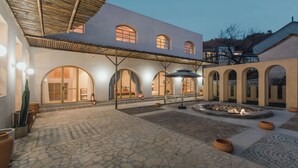 A courtyard with a stone floor, arched windows, and a covered seating area. - Qiran Rustic Resort Villa (Huairou)