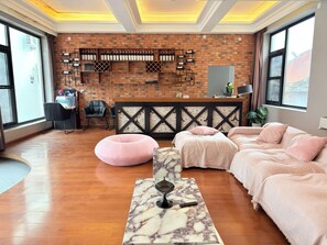 Una habitación de hotel con pared de ladrillo, cama, escritorio y ventana.