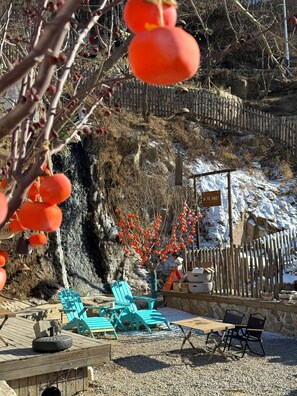 A patio area with outdoor seating, a wooden table, and a sign indicating a nearby attraction. - Qiran Rustic Resort Villa (Huairou)
