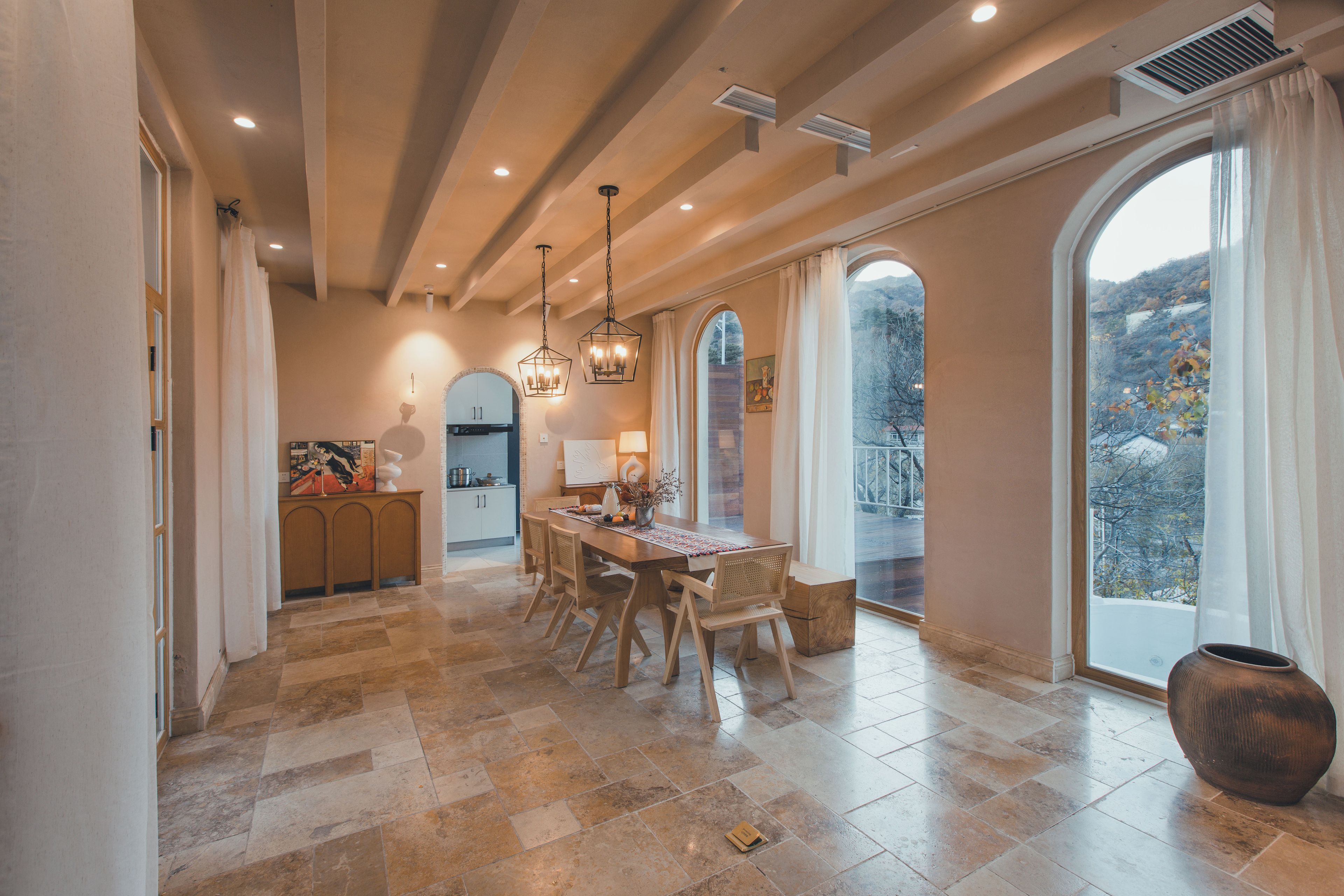 Un comedor espacioso con techo alto, ventanas grandes y vistas al exterior.
