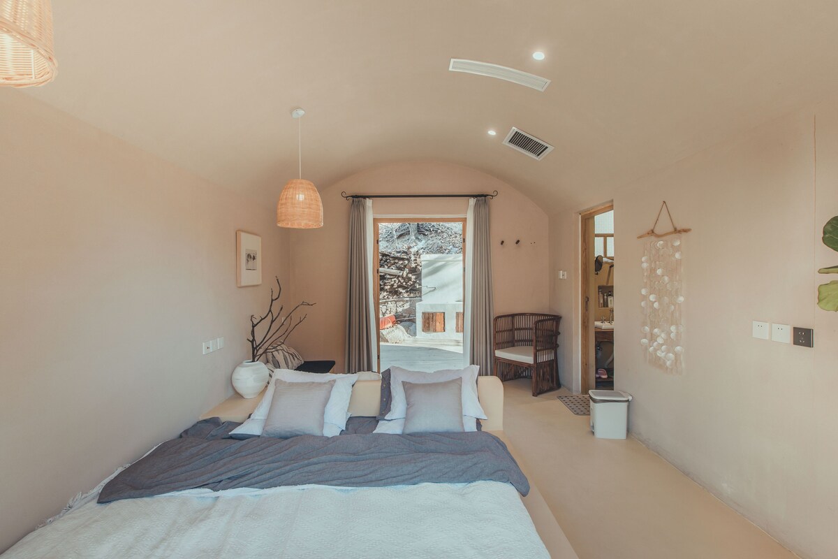 Un dormitorio con cama, una lámpara colgante, una ventana y vistas al exterior.
