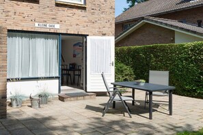 A brick house with a sign reading 'Kleine Oase' and a patio with a table and chairs. - Holiday apartment with 1 bedroom (Zoutelande)
