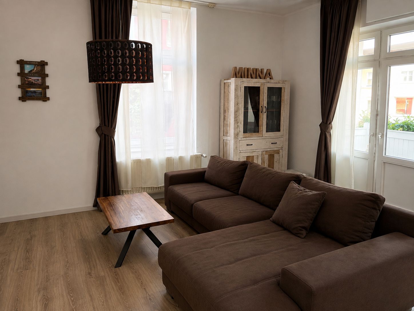 Un salon avec un canapé marron, une table basse en bois, un meuble et une lampe.
