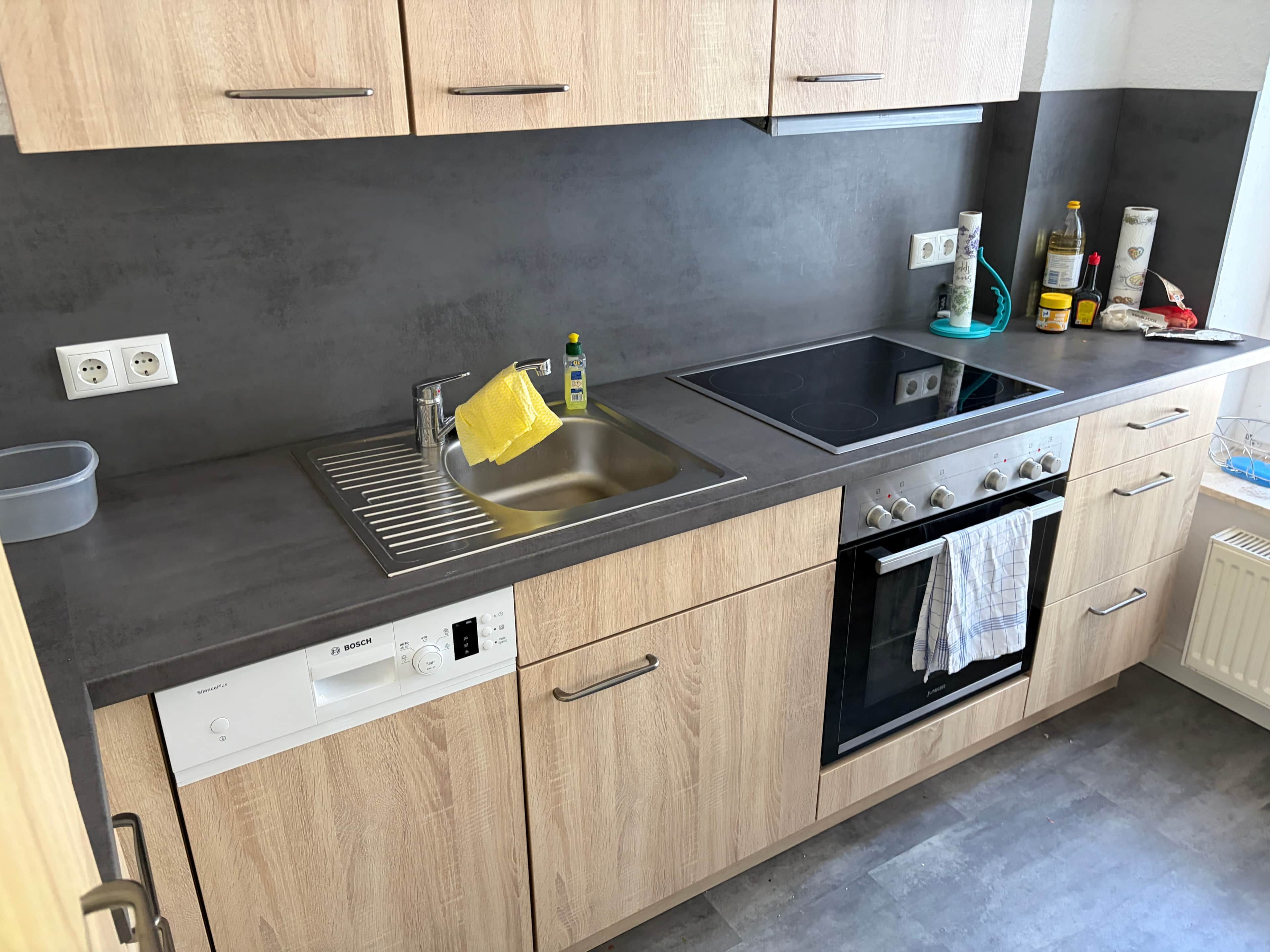 Una cucina moderna con lavastoviglie Bosch, lavello, fornello e pensili in legno.