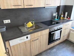Una cuina moderna amb un rentaplats Bosch, un rentamans, una placa de cocció i armaris de fusta.