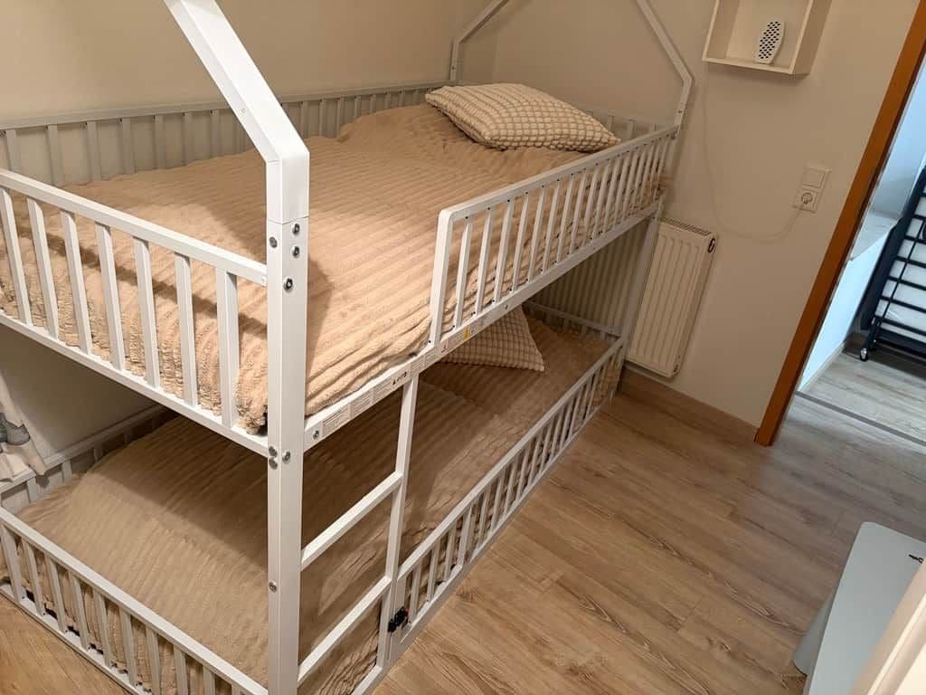 A bunk bed with a white frame, a mattress, and a pillow.