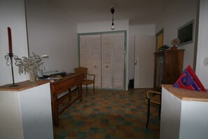 A room with a checkered floor, a desk with a chair, a wardrobe, and a cabinet with a plant. - Holiday home in Serignan with swimming pool (Serignan)