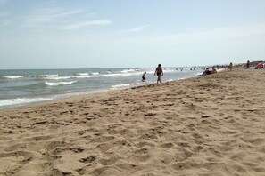 A sandy beach with people walking and swimming, and a clear sky. - Holiday home in Serignan with swimming pool (Serignan)