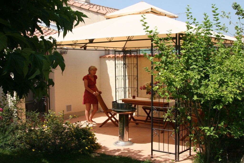 A patio area with a table and chairs, a grill, and a person walking.