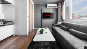 A modern living room with a grey sofa, a coffee table, and a flat-screen TV mounted on the wall. - SUN FRIENDS 201 (Asahikawa)